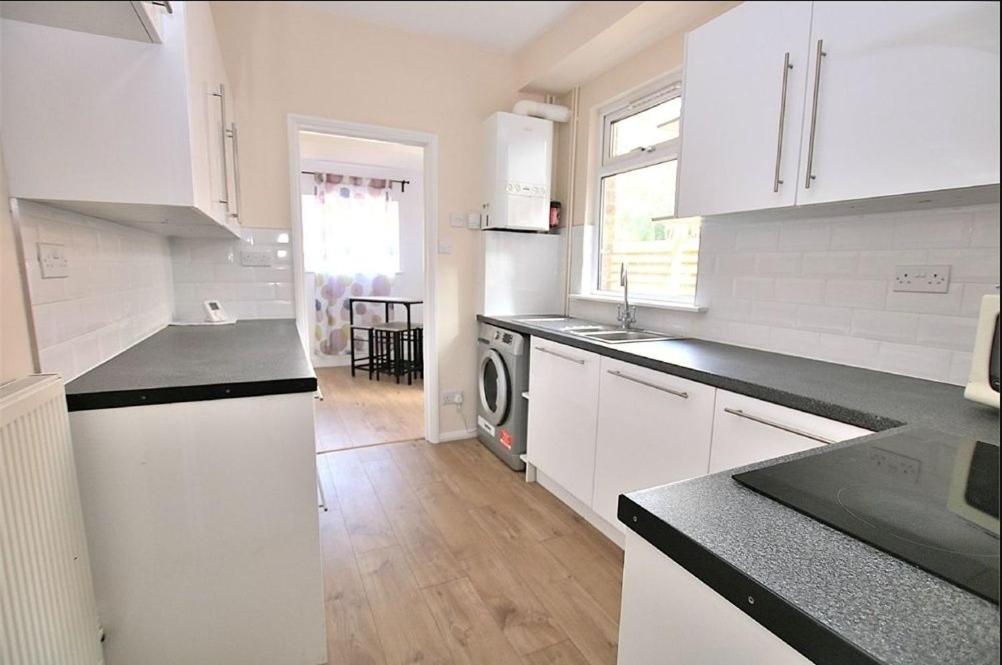 a kitchen with white cabinets and black counter tops at Hood St in Kingsthorpe