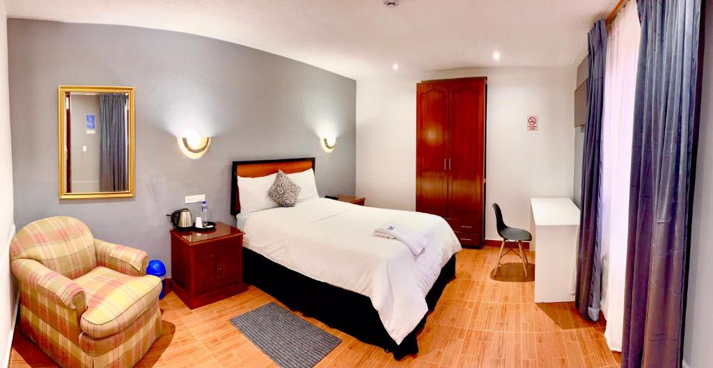 una camera d'albergo con letto e sedia di Quinta San Carlos Hostel a Ibarra