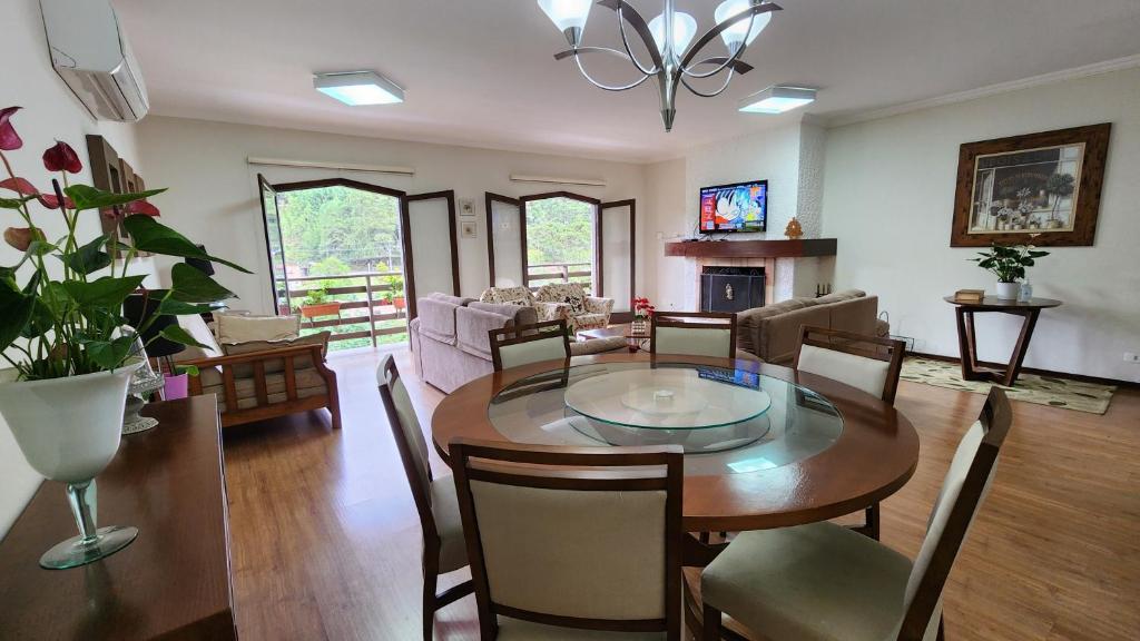 - une salle à manger et un salon avec une table et des chaises dans l'établissement Apto no centro turístico Capivari (150m do Baden), à Campos do Jordão
