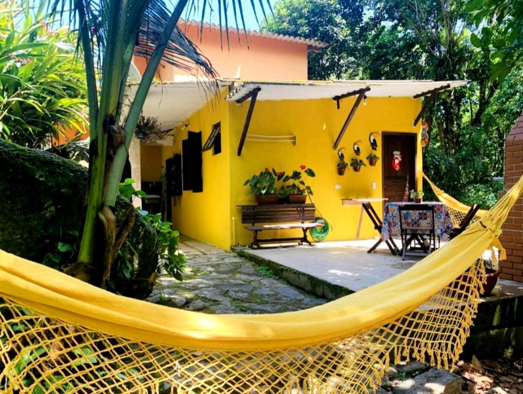 a yellow house with a hammock in front of it at Chalé da cachoeira - Ilhabela in Ilhabela