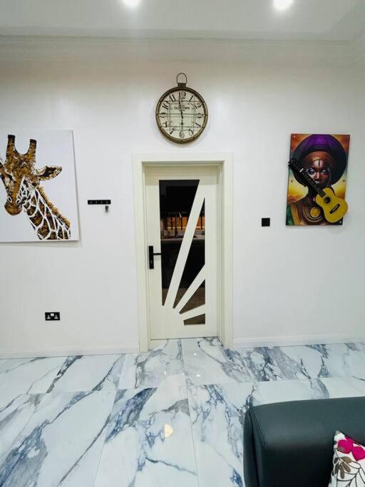 una stanza con una porta e un orologio sul muro di Not Like The Rest of ‘Em! a Lagos