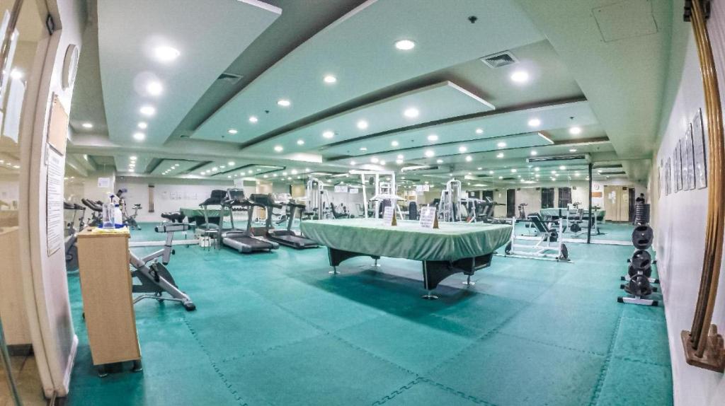 a large room with a gym with a green floor at Robinson manila birchtower in Manila