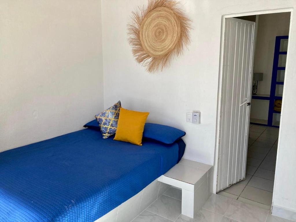 Habitación con cama con sábanas azules y almohadas amarillas. en Casa Isla Delfín, en Lo de Marcos