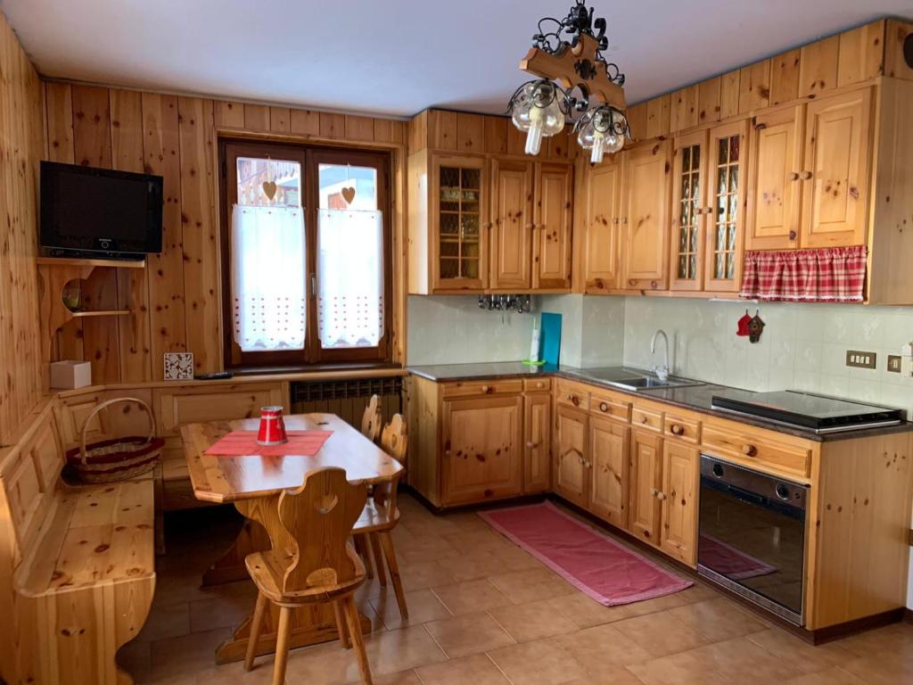 a kitchen with wooden cabinets and a table and a tv at CASA PIAZZALE ALPINI in Schilpario