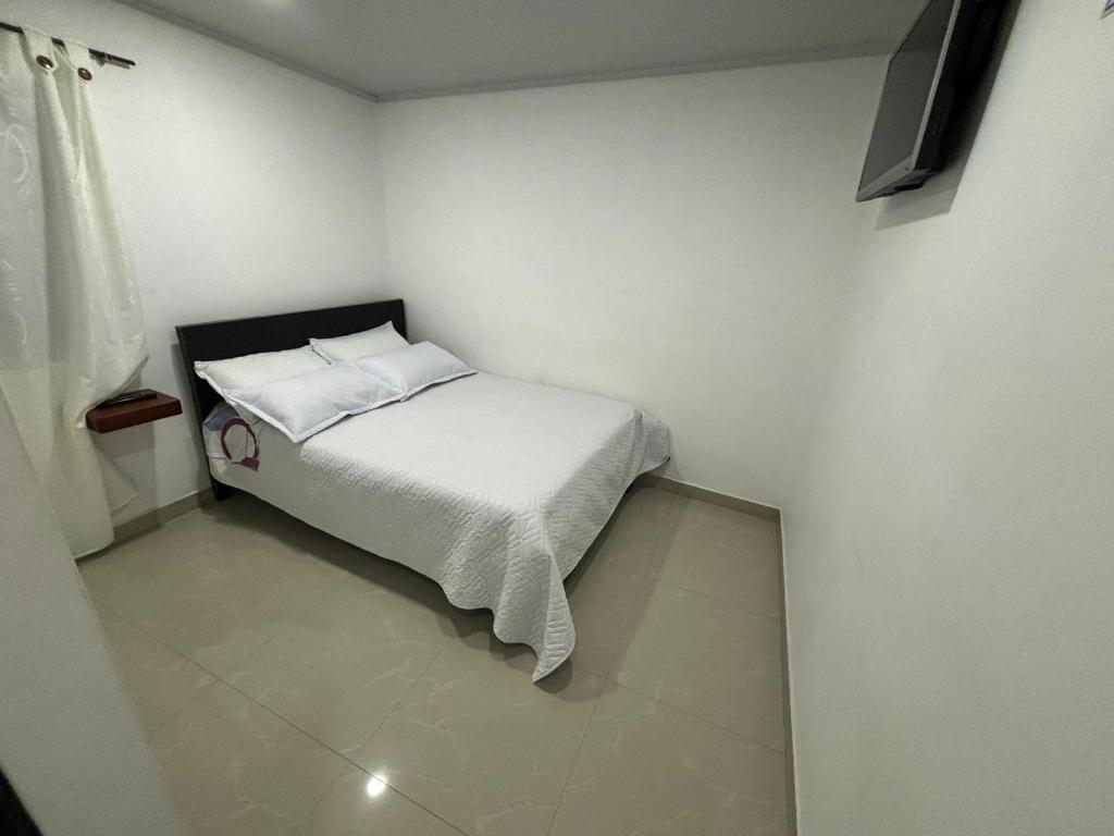 ein kleines Schlafzimmer mit einem Bett mit weißer Bettwäsche in der Unterkunft HOTEL TUNJA ALEJANDRIA in Tunja