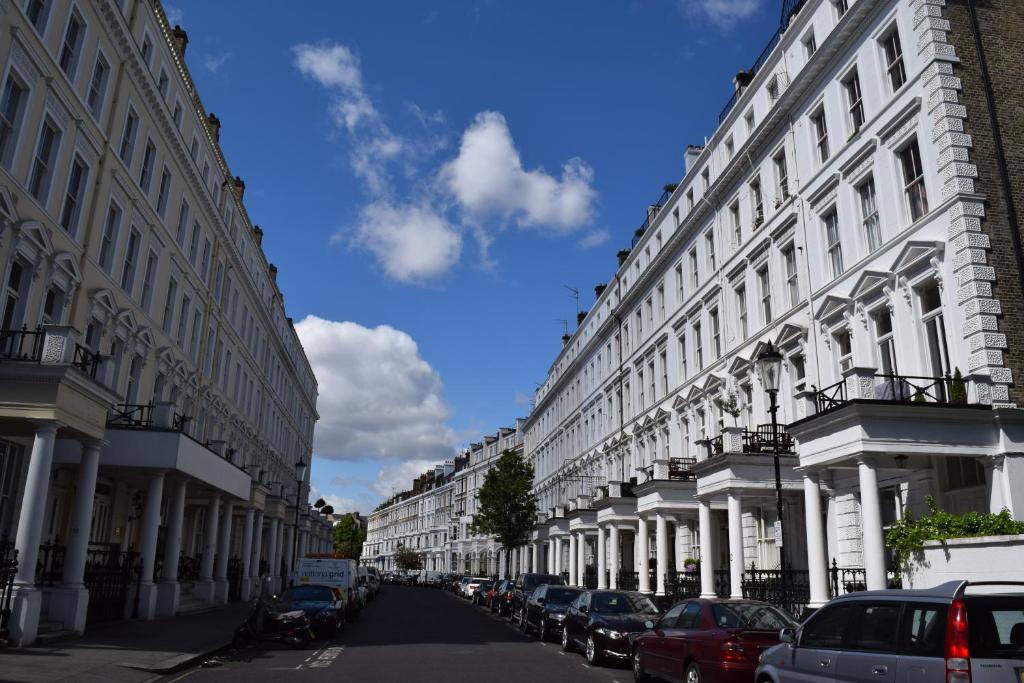a row of buildings on a street with parked cars at Kensington Apartments in London