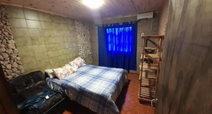 1 dormitorio con cama y cortina azul en Alquiler playa Quequén, Necochea Buenos Aires en Quequén