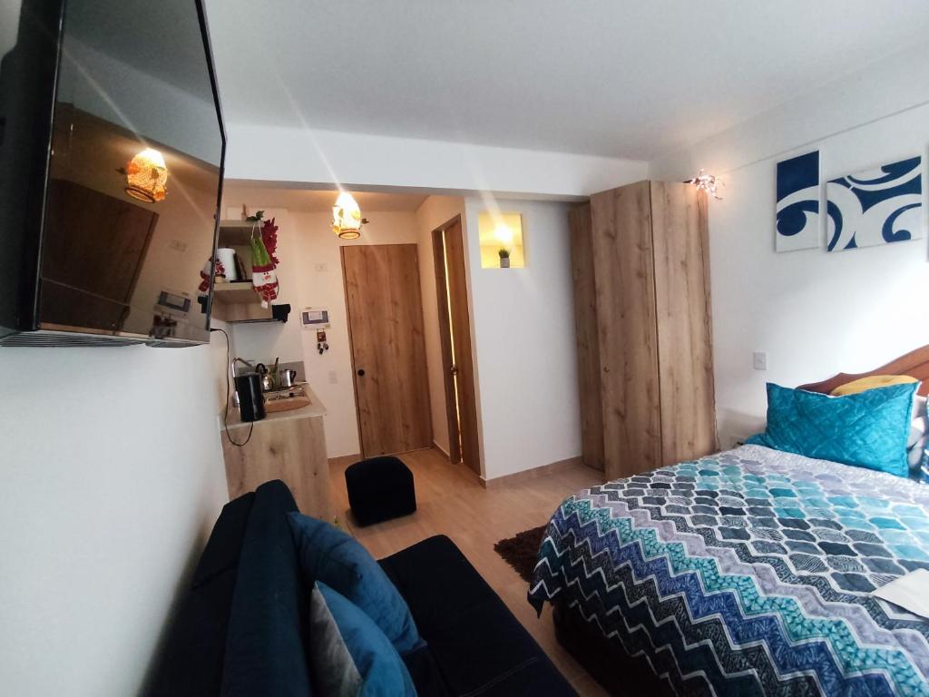 a bedroom with a bed with a blue comforter at Aparta estudio en la candelaria WiFi rápido-a pasos del museo de oro in Bogotá