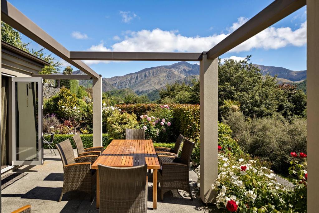 a patio with a table and chairs with mountains in the background at Elite Holiday Homes Queenstown - Arrowbrae in Arrowtown