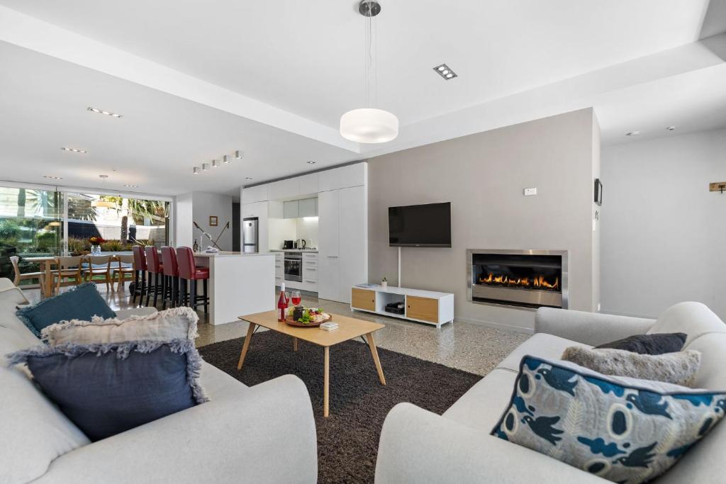 a living room with white furniture and a fireplace at Sanctuary on Kent in Queenstown