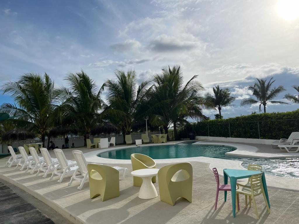 a group of chairs and tables next to a swimming pool at Playa La Barqueta , Las Olas Tower Front in David