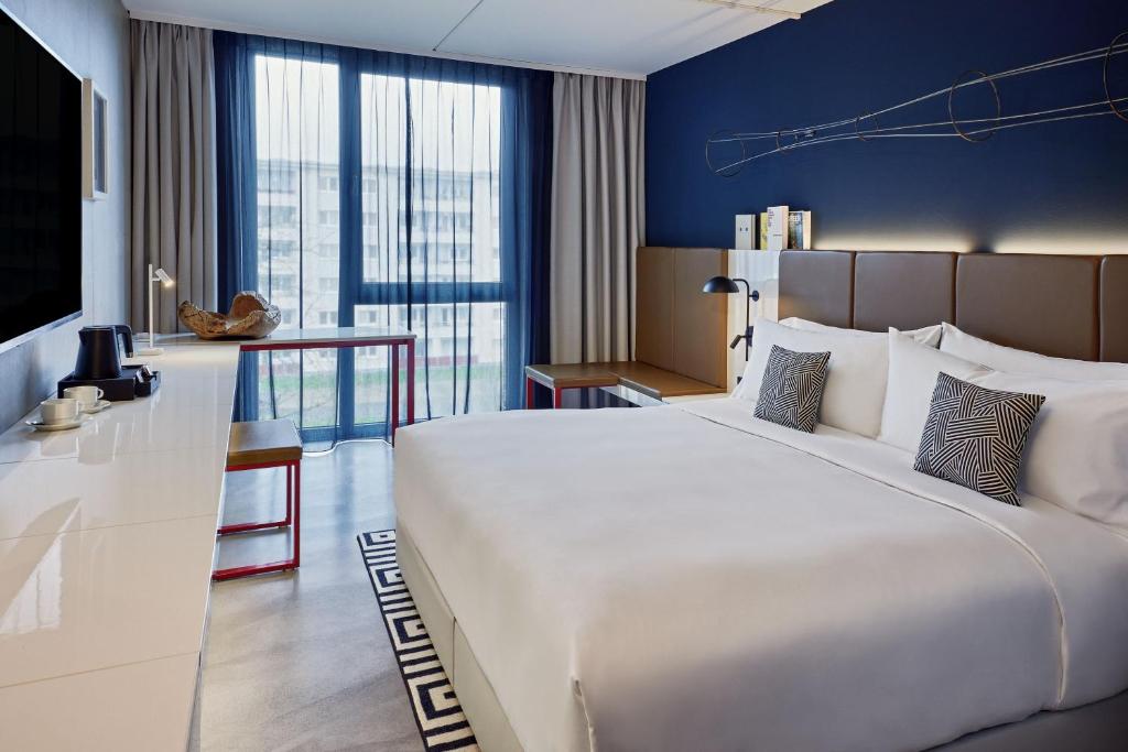 a hotel room with a large bed and a desk at the Deutz, a Tribute Portfolio Hotel in Cologne