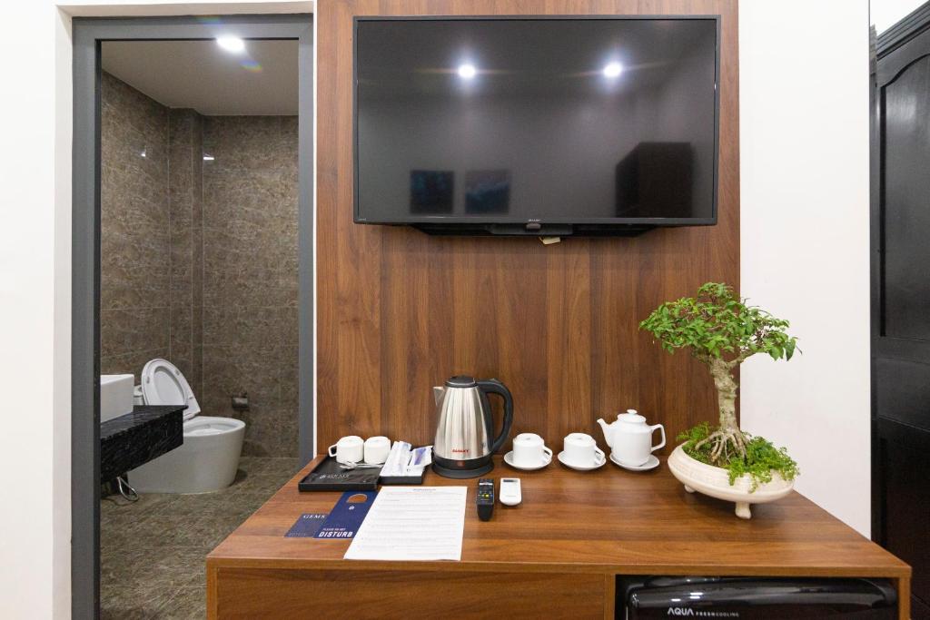 TV en la pared en el baño con mesa en Gems Hotel - Khách sạn Trảng Bàng, en Trảng Bàng