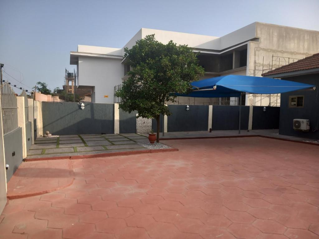 a house with a patio and a blue umbrella at Anc mall area east legon guest house in Accra