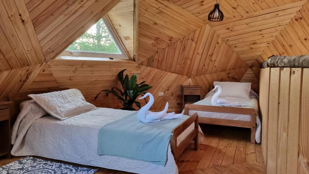 sypialnia z 2 łabędzami na łóżkach w drewnianym domku w obiekcie ANGEL DOMO w mieście Puerto Montt