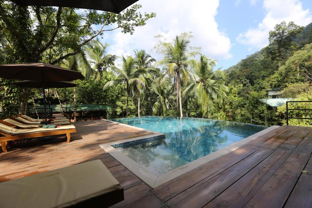 einen Pool mit einer Holzterrasse und einem Resort in der Unterkunft 360 Rainforest in Deniyaya