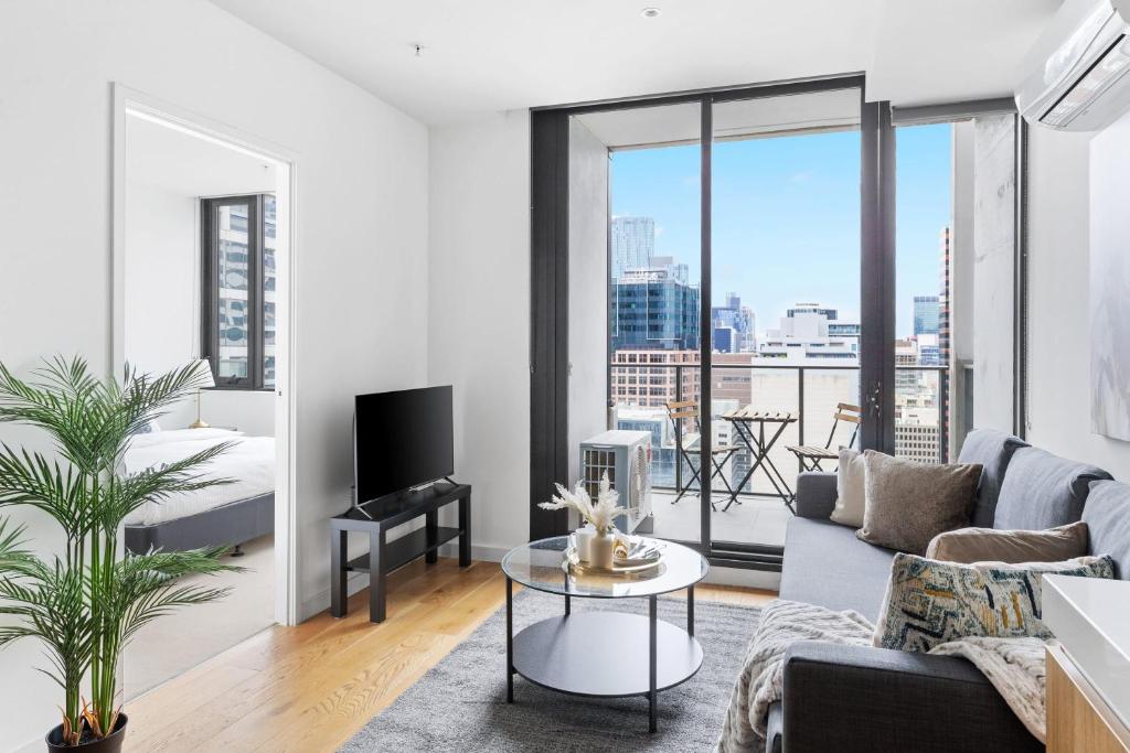 een woonkamer met een bank en een tv bij Modern 2BR Apt Next to Southern Cross FREE Parking in Melbourne