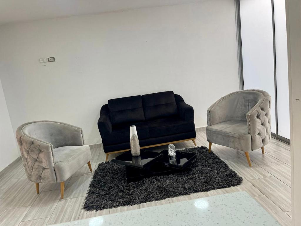 two chairs and a black couch in a living room at Hermosa casa in Cúcuta