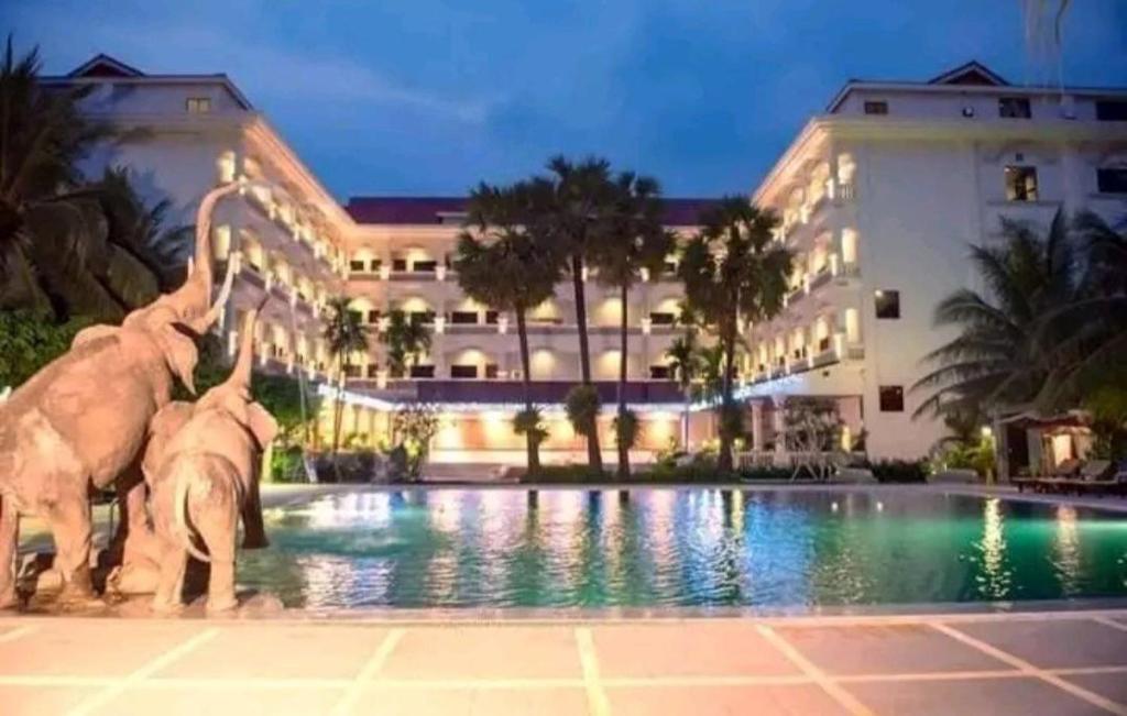 a hotel with two elephants standing in a pool at Ree Mohasambath Hotel & Resort in Phumĭ Thnál
