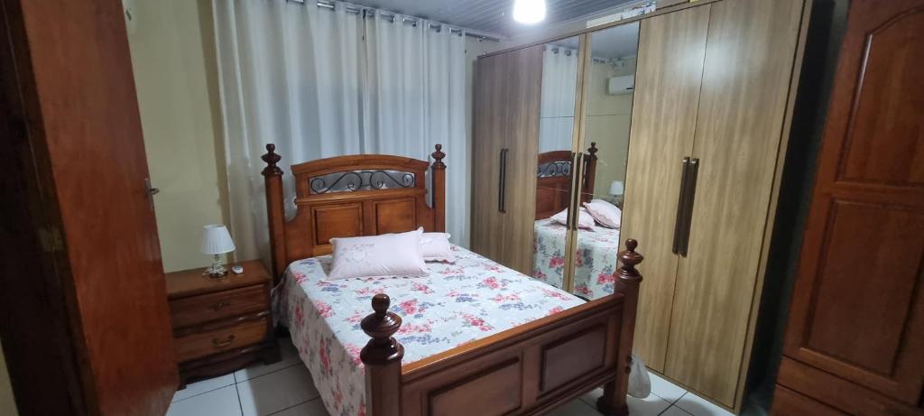 casa da Gilvana في ساو غابرييل: غرفة نوم بسرير خشبي ومرآة