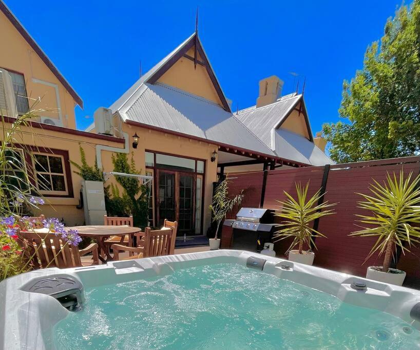 a large hot tub in front of a house at Porters Cottage Classic in Albury
