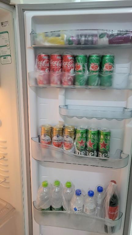 - un réfrigérateur ouvert rempli de boissons et de sodas dans l'établissement Apartamento em Araguari, à Araguari