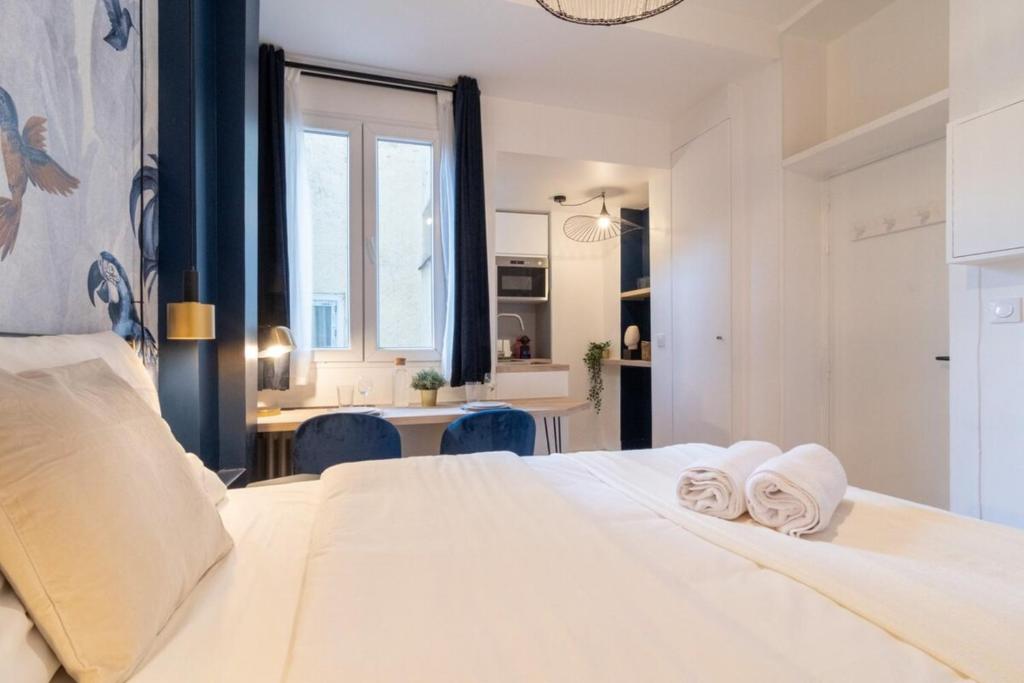 una camera da letto con un letto bianco con asciugamani sopra di Equipped studio in the center of Lille a Lille