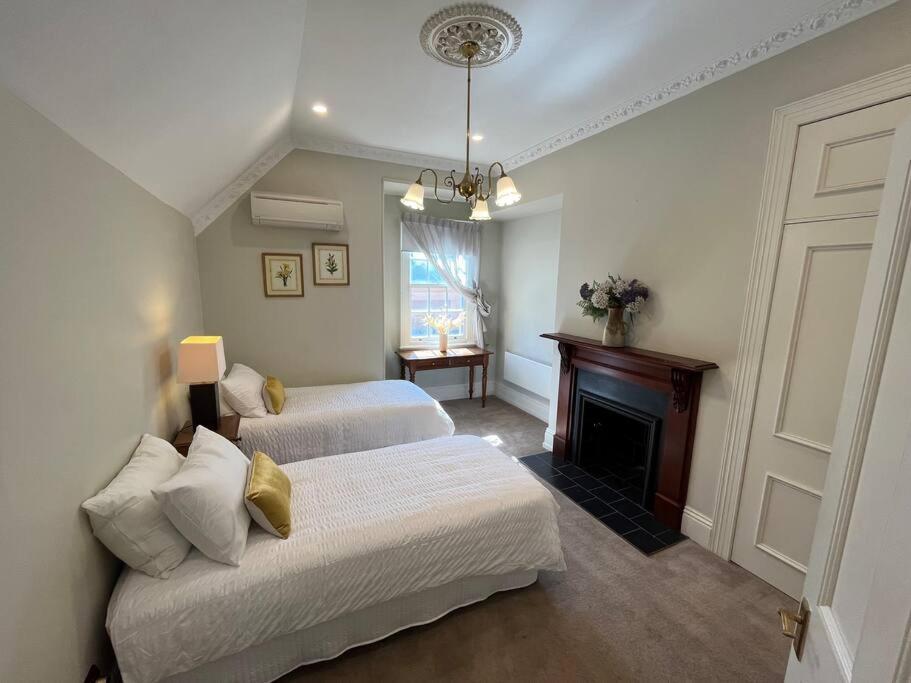 a bedroom with two beds and a fireplace at Porters Cottage Oasis in Albury