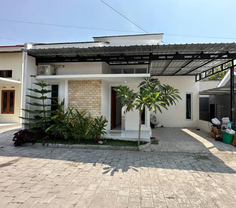 Mahardika Homestay Gamping في سليمان: بيت أبيض مع شجرة نخيل أمامه