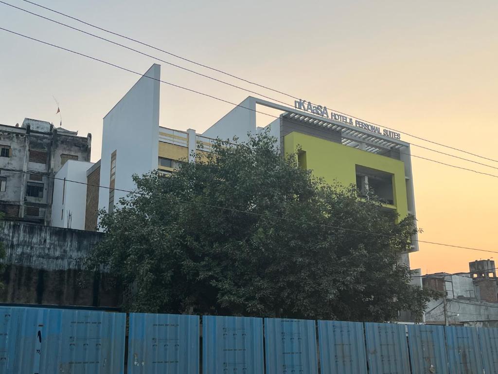 um edifício atrás de uma cerca com uma árvore em frente em nKAaSA hotel Personal Suites em Raxaul