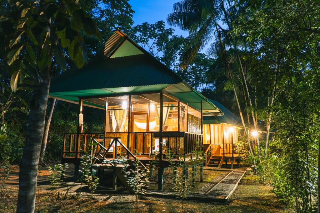 une petite maison avec un toit vert dans les bois dans l'établissement Passiflora Camp, à Puerto Maldonado