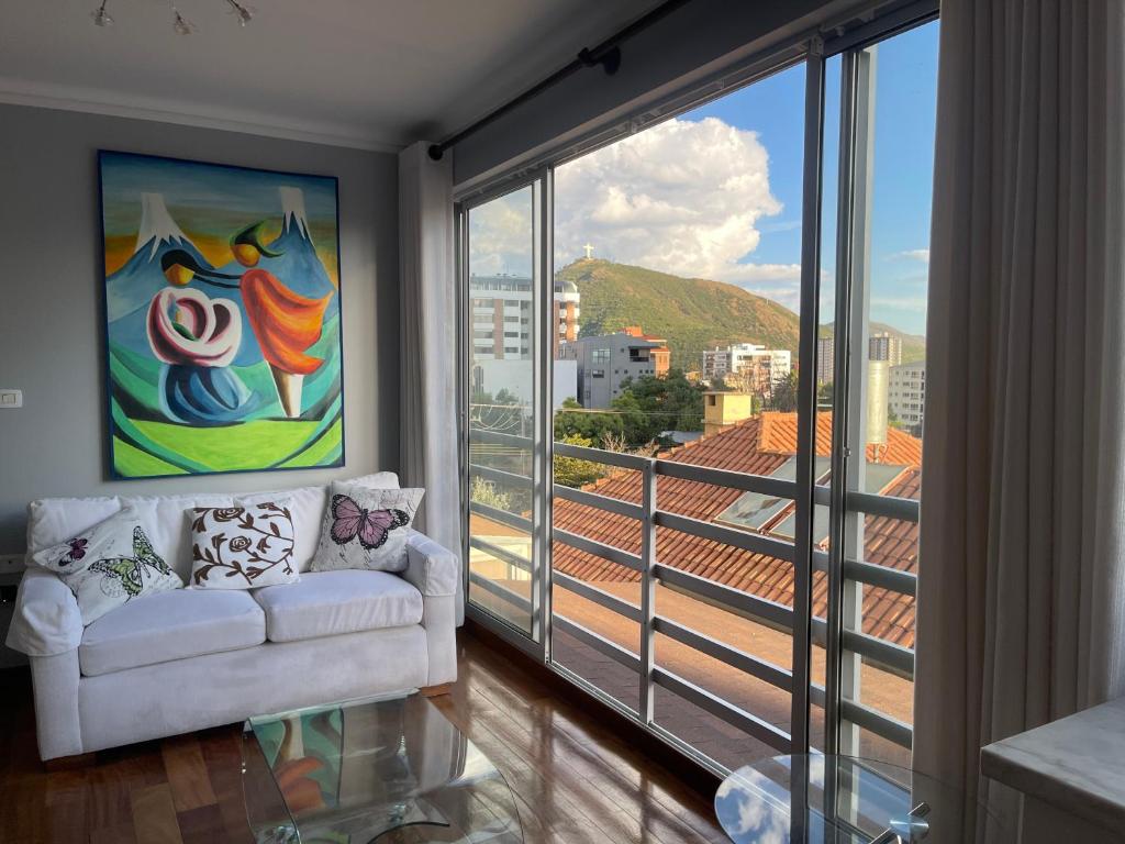 a living room with a couch and a large window at Lujoso departamento en ¨torre Alessandria¨ in Cochabamba