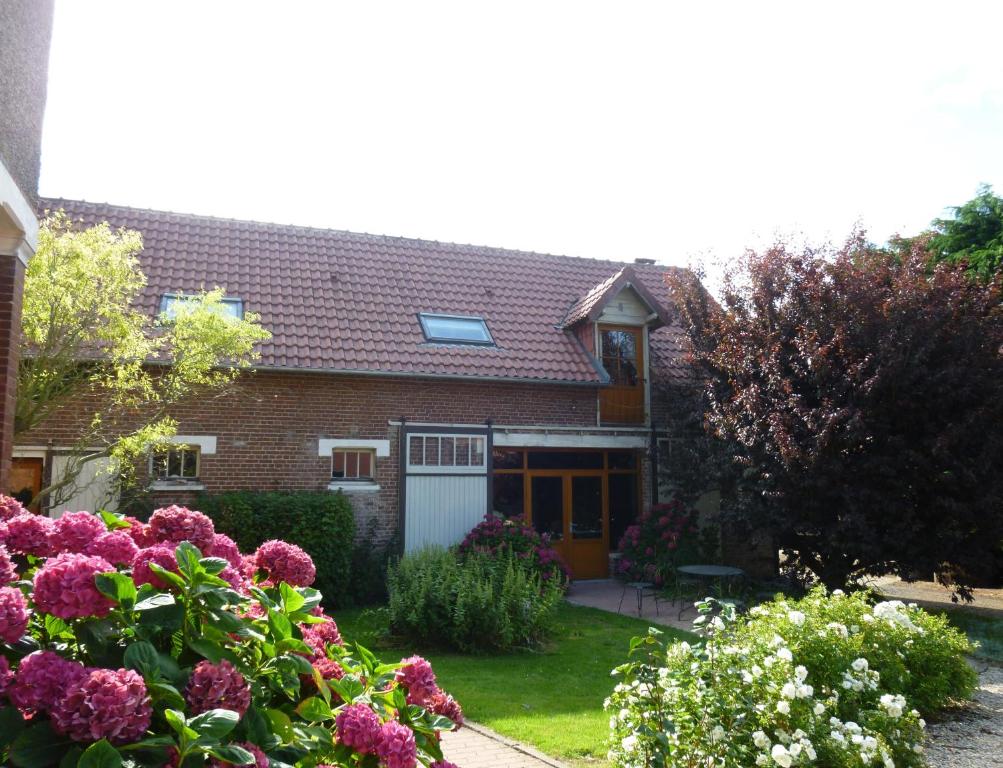 a brick house with flowers in the yard at La Cense des 6 Sens in Beugny