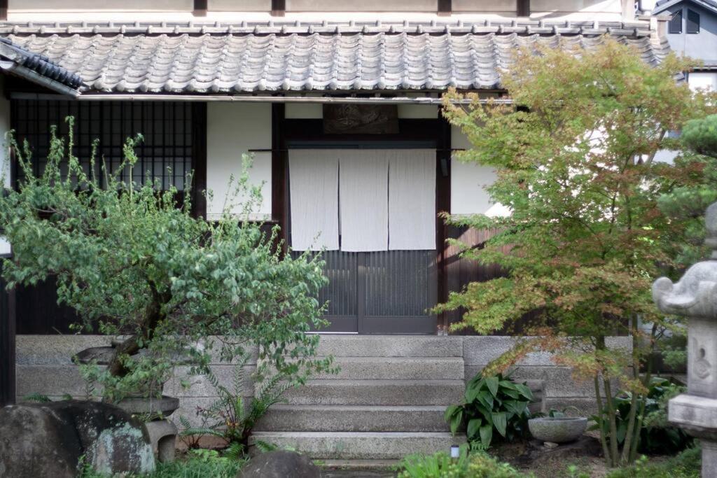 にある日々の宿: 宇野駅から車で5分 直島へ 最大7名様 古民家貸切 一棟貸しの白い扉と木々のある家