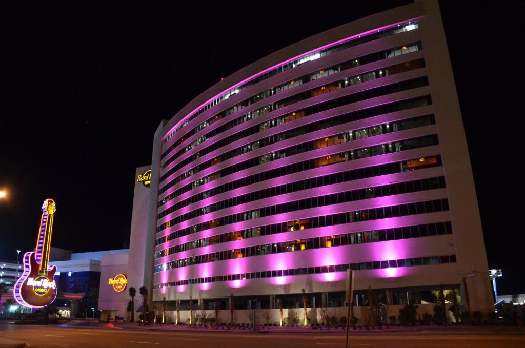 ein großes Gebäude mit lila Lichtern in der Nacht in der Unterkunft Hard Rock Hotel &amp; Casino Biloxi in Biloxi