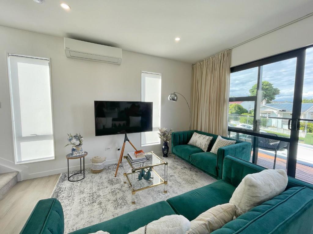 salon z zieloną kanapą i telewizorem z płaskim ekranem w obiekcie Your Modern Home in Sandringham, Close to City, Heat Pumps, Netflix, Parking w Auckland