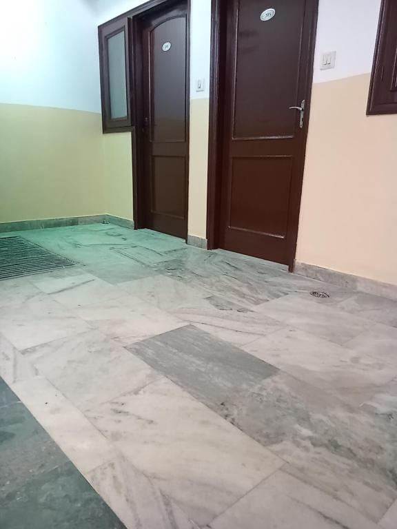 um quarto vazio com duas portas e um piso de mármore em Om Sai palace em Chandīgarh
