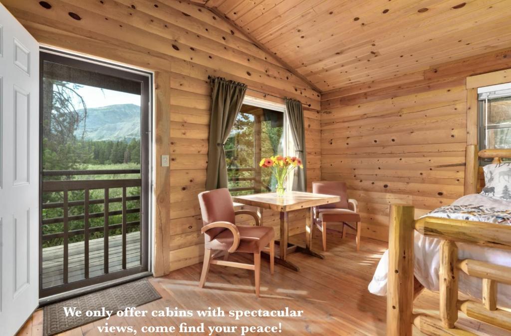 a log cabin with a table and chairs and a balcony at Summit Mountain Lodge and Steakhouse in East Glacier Park