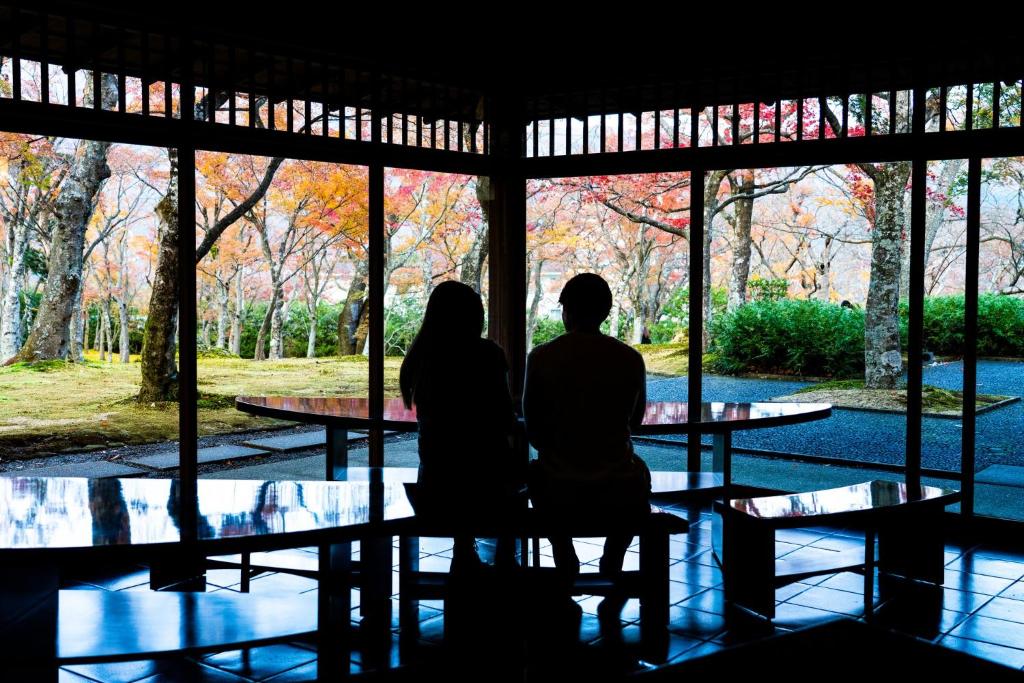 una coppia seduta su una panchina di fronte a una finestra di Hotel Indigo Hakone Gora, an IHG Hotel a Hakone