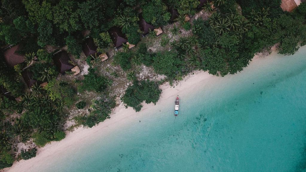 The Sevenseas Resort Koh Kradan في كوه كرادان: اطلالة جوية على شاطئ يوجد قارب عليه