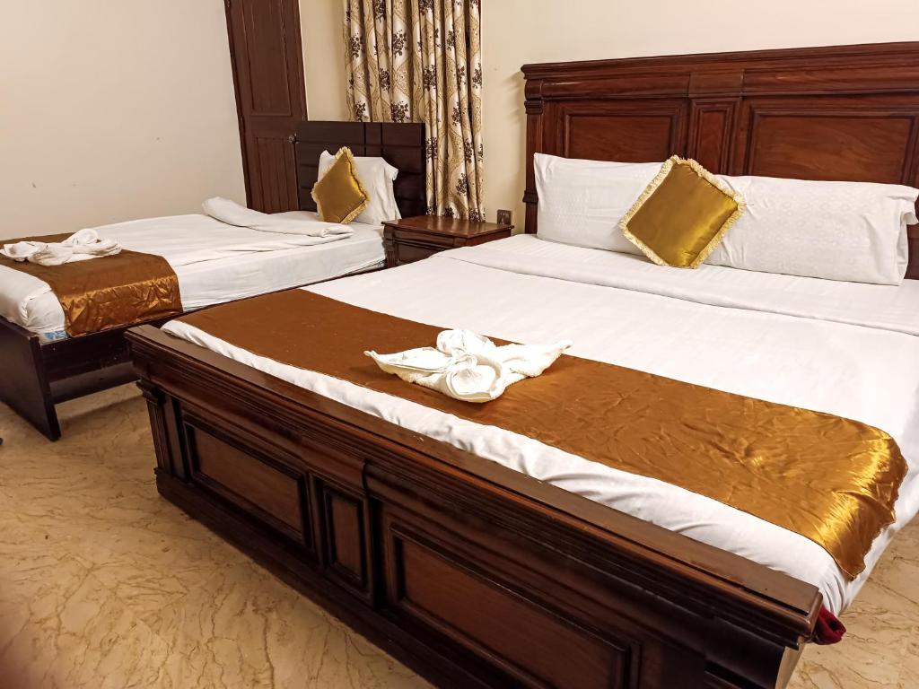 two beds in a hotel room with towels on them at Luxury Living Rooms in Karachi