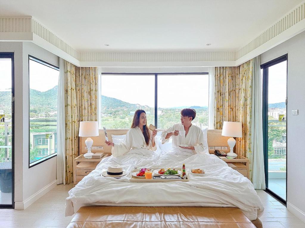 um homem e uma mulher sentados numa cama num quarto de hotel em Amari Hua Hin em Hua Hin