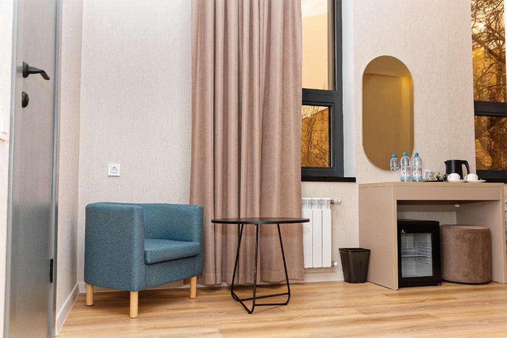 a living room with a blue chair and a table at Aston Hotel in Aktau