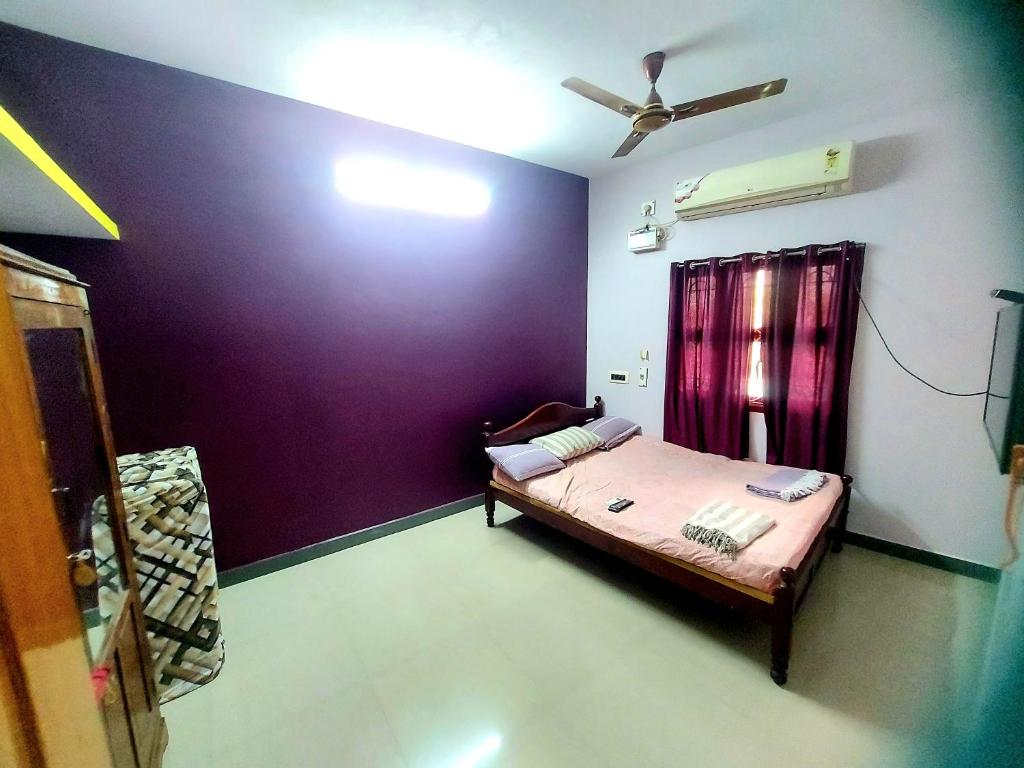 um quarto com uma cama e uma parede roxa em CASA DEEPAM em Pondicherry