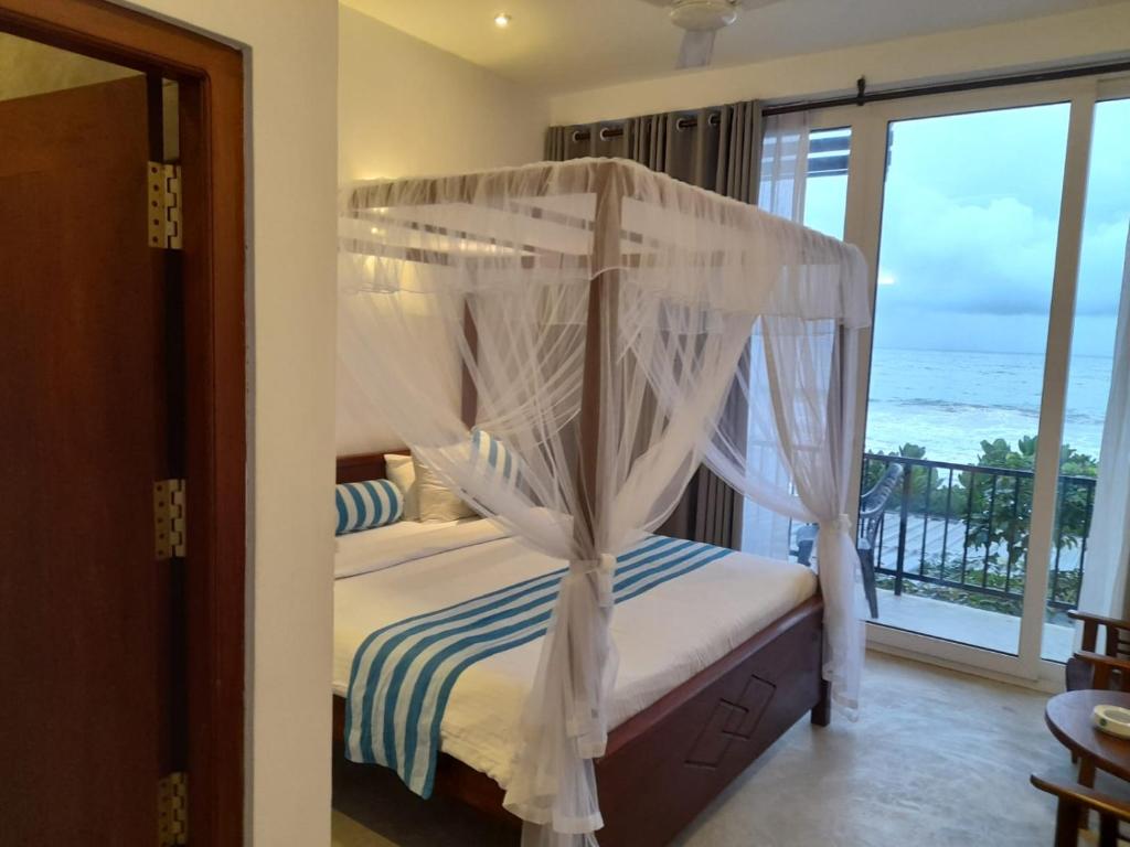 a bedroom with a canopy bed with a view of the ocean at Brizo Resort in Mirissa