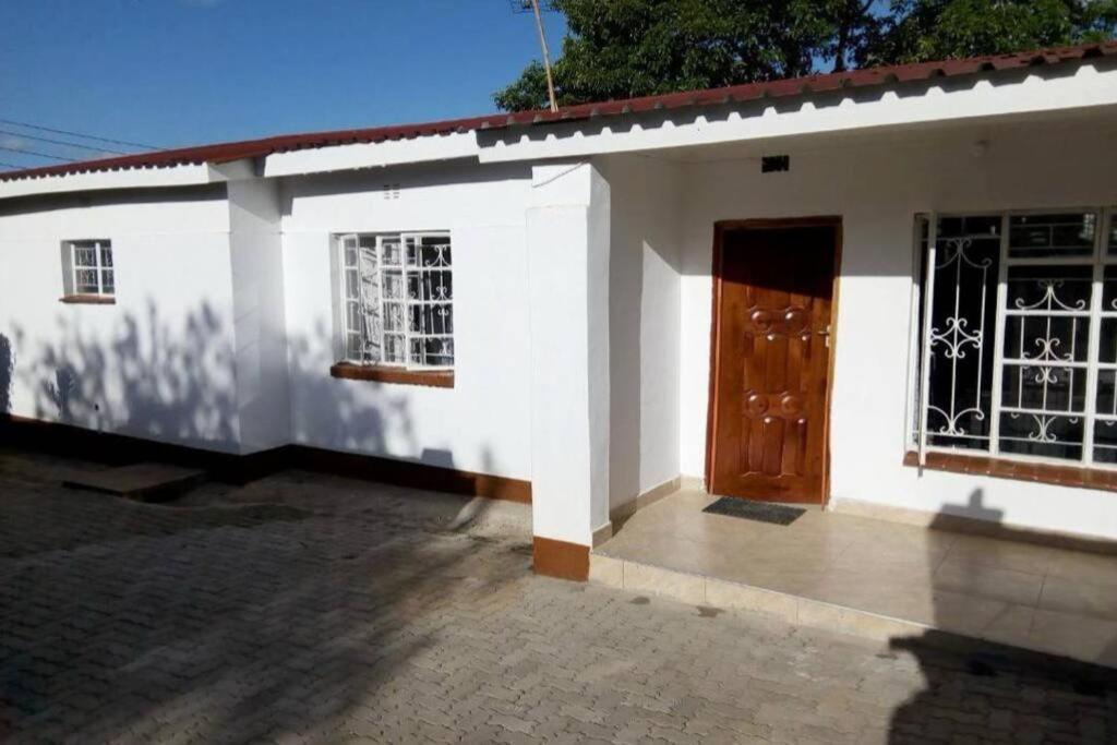 a white house with a door and a window at Nichi's Guesthouse - Cosy 3 bedroom with breakfast in Blantyre
