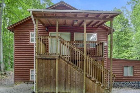 a large wooden cabin with a deck in the woods at Cuddles, 1 Bedroom Studio, Walk to Downtown and Hiking Trails! in Gatlinburg