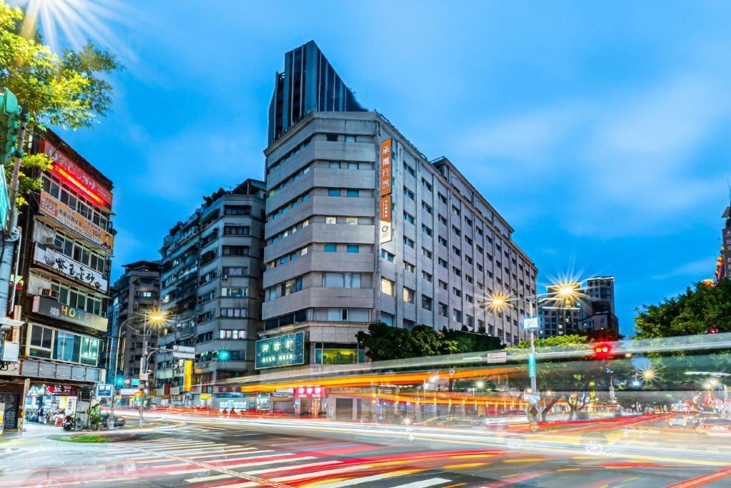eine Stadtstraße in der Nacht mit einem hohen Gebäude in der Unterkunft Guide Hotel Taipei Chongqing in Taipeh