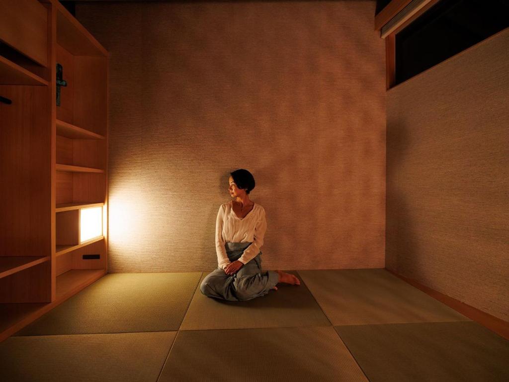 a woman sitting on the floor in a room at Denpaku The Beachfront MIJORA in Amami