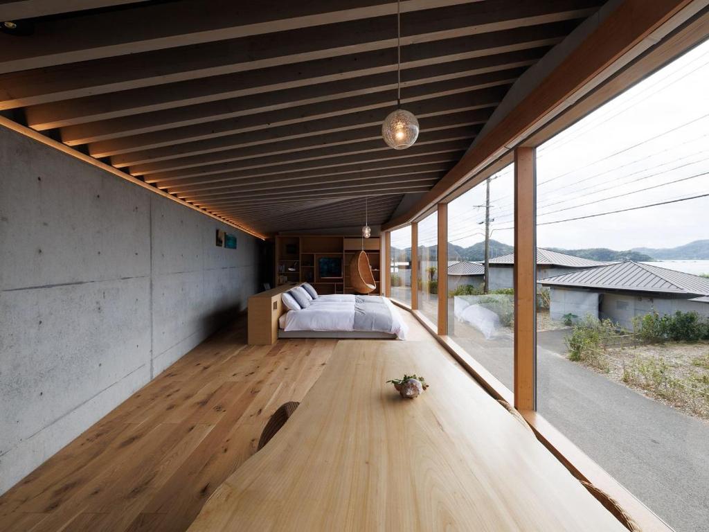 a bedroom with a bed and a wooden floor at Denpaku The Beachfront MIJORA in Amami